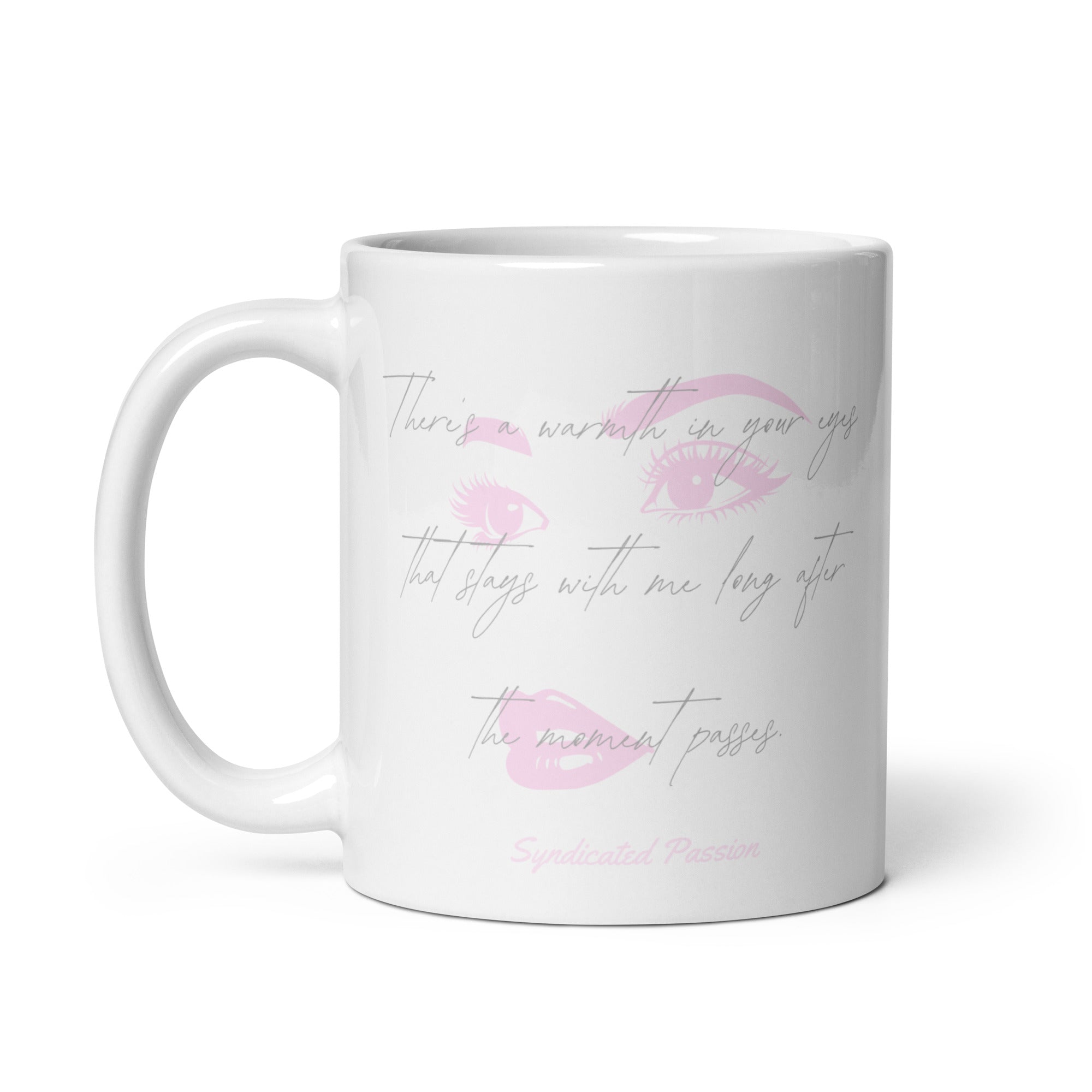 A white ceramic coffee mug with a pink lip print and cursive text that reads 'There's a warmth in your eyes that lingers with me long after the moment passes', with 'Syndicated Passion' printed at the bottom.