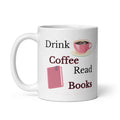 A white ceramic coffee mug with a printed graphic that reads 'Drink Coffee Read Books' in black and dark red text, accompanied by illustrations of a pink polka-dot coffee cup and a pink book. By Syndicated Passion at the bottom. 