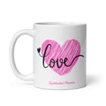 White glossy 11 oz ceramic mug with bold black cursive 'love' script over a vibrant hand-drawn pink scribble heart illustration — a romantic Valentine's Day gift for her by Syndicated Passion®